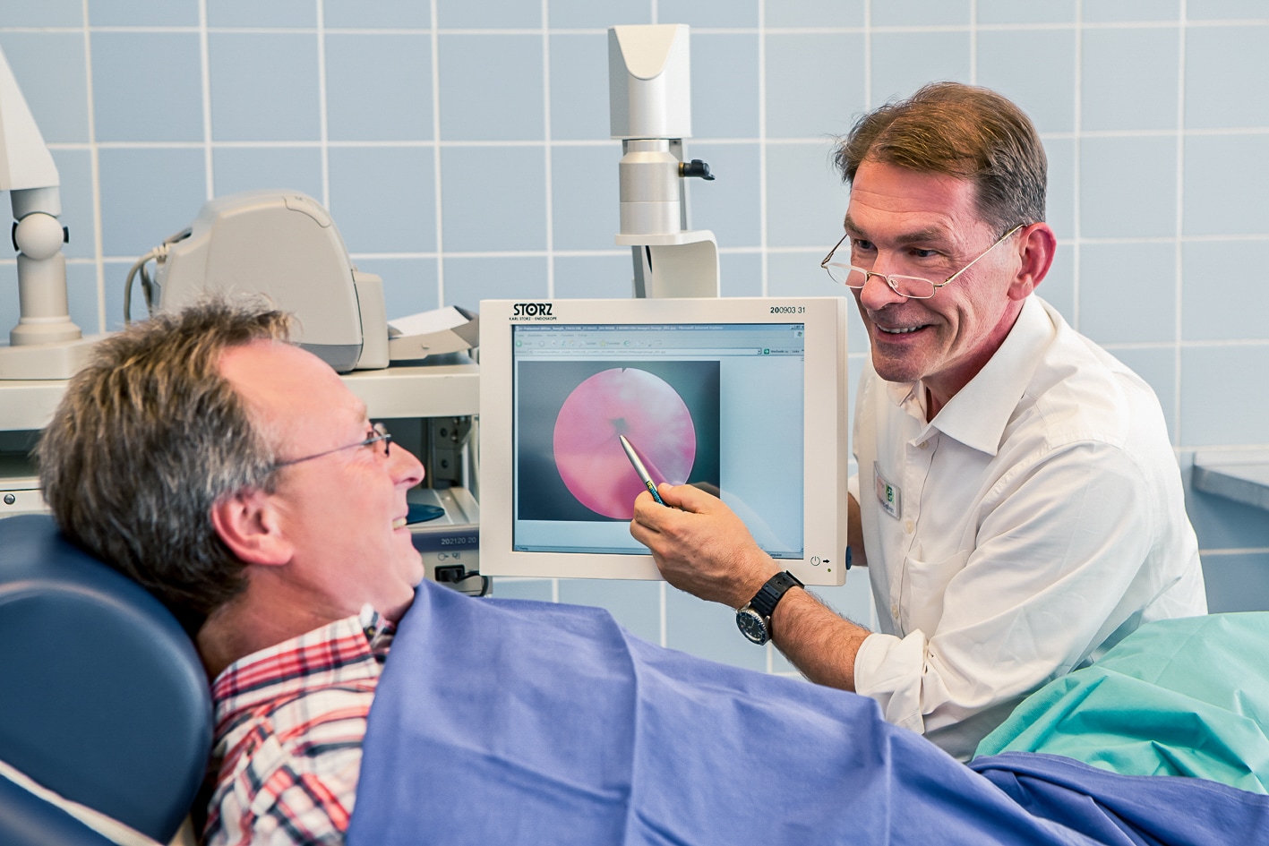 Arzt erklärt Patient während der Behandlung etwas auf dem Bildschirm
