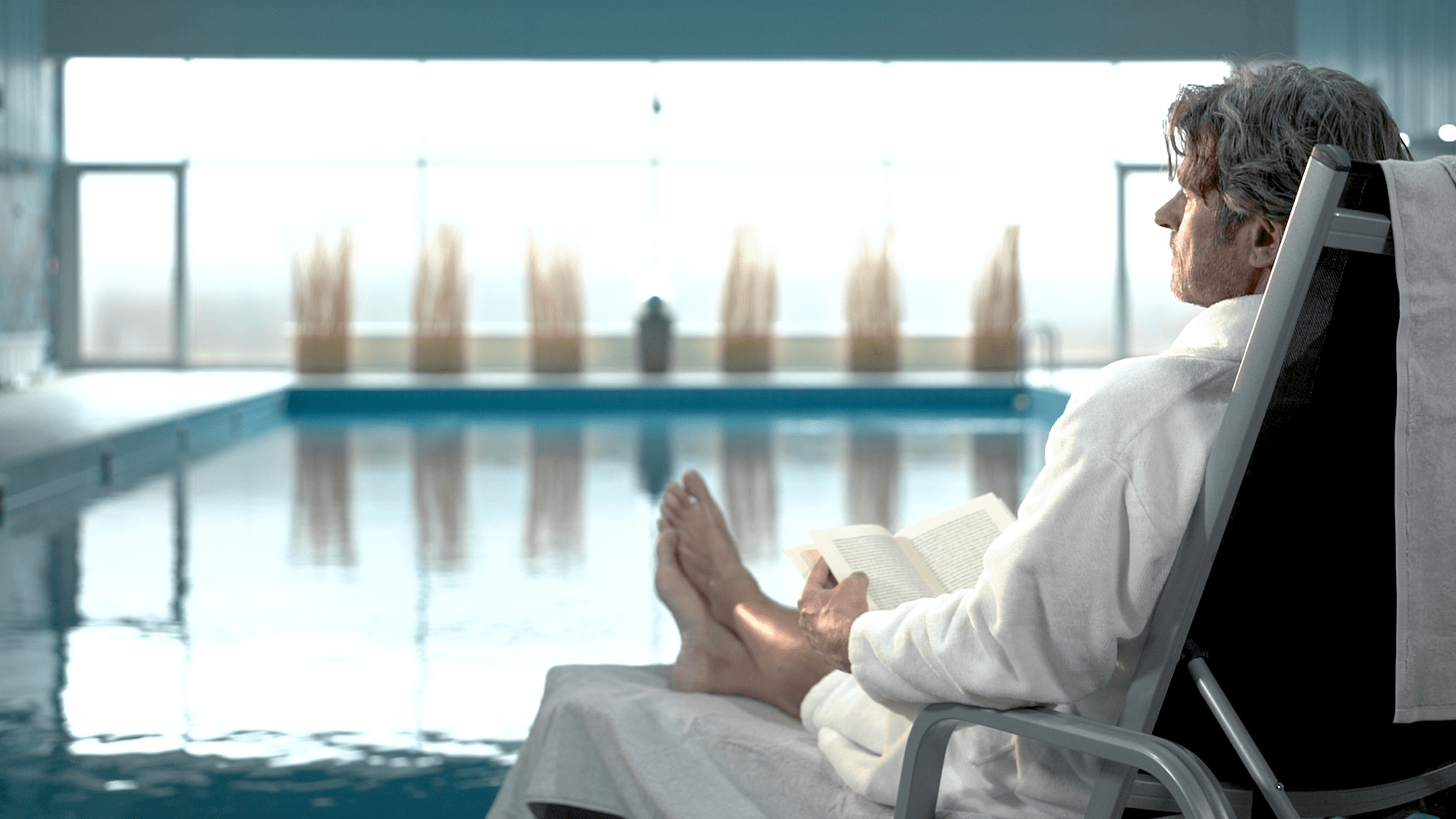 Patient liegt auf einer Liege am Pool und liest